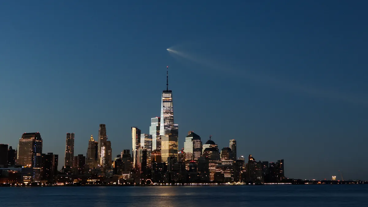 A SpaceX Falcon 9 rocket on the Starlink Group 10-49 mission passes by lower Manhattan and One World Trade Center just before dawn in New York City after launching from Cape Canaveral, Florida on Aug. 25, 2026, as seen from Hoboken, New Jersey. (Image credit: Getty Images)